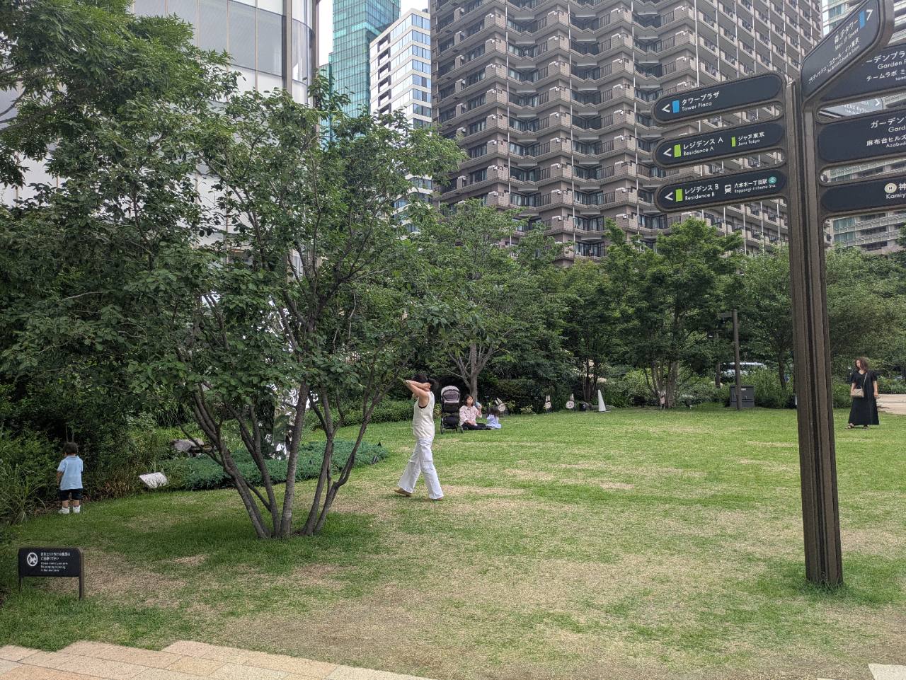 麻布台ヒルズの芝生広場。高層ビルに囲まれた緑豊かな空間で家族連れが思い思いに過ごしている