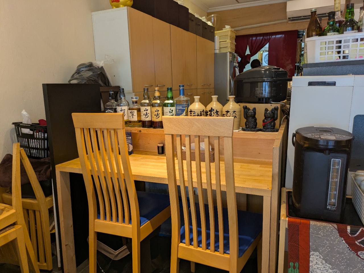 麻布あみ城の店内。木のカウンター席と椅子、ウイスキーボトルが並ぶ落ち着いた和食店の雰囲気