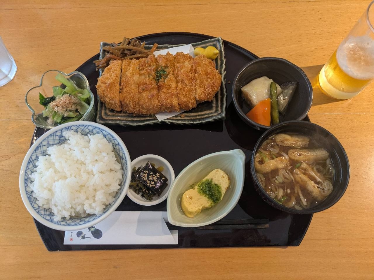 麻布あみ城のとんかつ定食。一汁五菜のスタイルで、ご飯、だし巻き卵、昆布佃煮、おひたし、小鉢、味噌汁が揃う