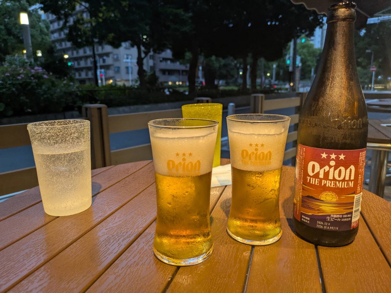 夕暮れのテラス席に置かれたオリオンビール THE PREMIUMの瓶とグラス